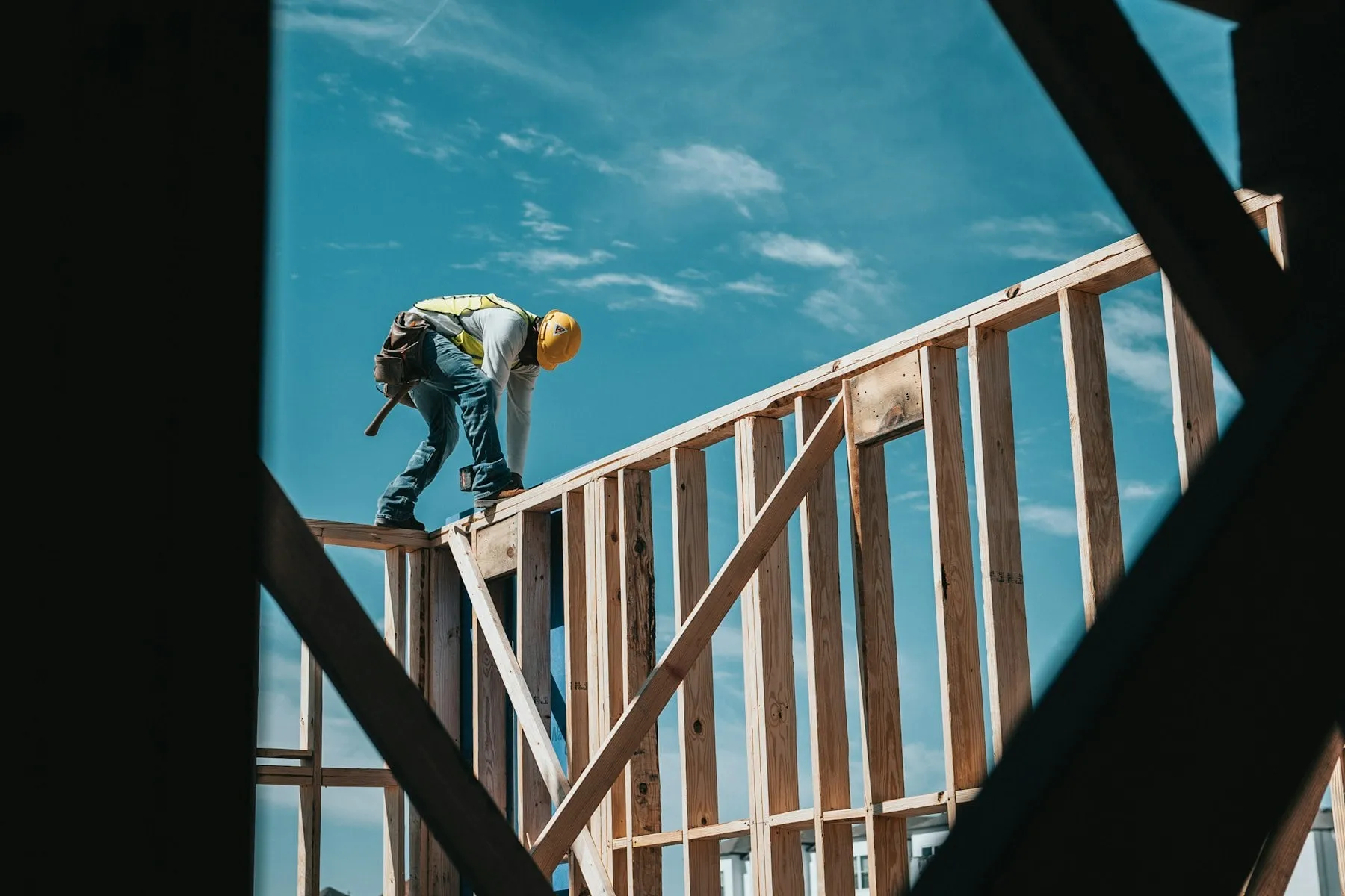 A construction worker in a hard hat on a timber building frame